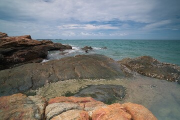 The seaside on a cloudy, windy day with large rocks in the foreground