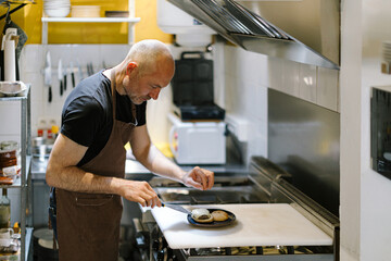 Chef finishing gourmet burger in restaurant kitchen
