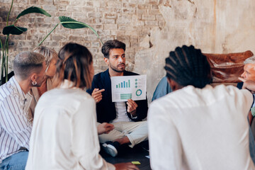 Marketing manager showing charts and statistics to his team during a meeting