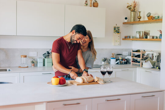 Couple laughing and slicing bread in a modern kitchen - Powered by Adobe