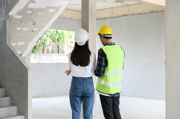 Female civil engineer with personal safety equipment check and consult with construction site...