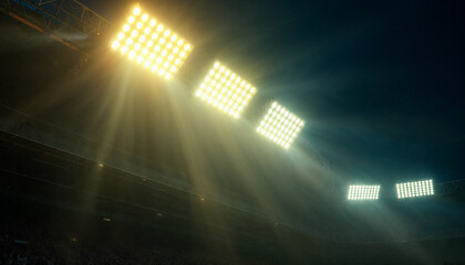 Close-up of bright stadium floodlights glowing against a dark night sky.