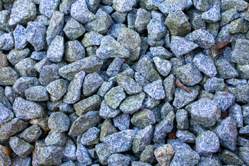 Pile of gray rocks. The rocks are small and are scattered around. There are some green spots on the rocks.