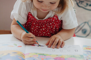 Little girl draws with pencil