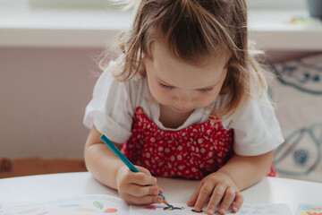 Little girl draws with pencil