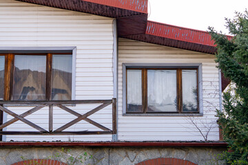 old abandoned dilapidated falling apart single-family house. house with falling wooden balustrade covered with white panels. old architecture.