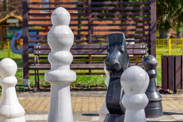 Giant Outdoor Chess Pieces.large white and black chess pieces arranged on an outdoor chessboard....