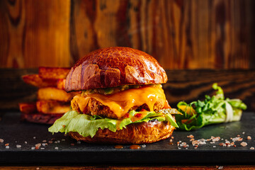 Fresh craft burger on a rustic wooden background. French fries on the side 