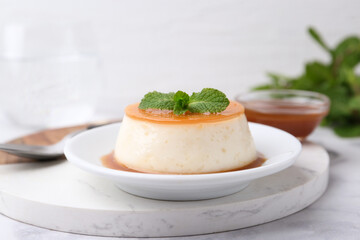 Tasty pudding with caramel sauce served on white marble table, closeup