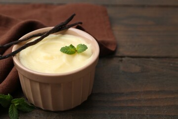Tasty vanilla pudding, mint and pods on wooden table, closeup. Space for text