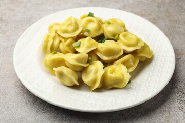 Tasty dumplings with green onion on grey textured table, closeup