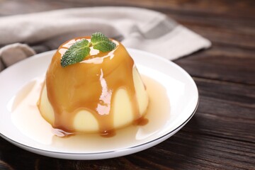 Delicious pudding with caramel sauce and mint on wooden table, closeup