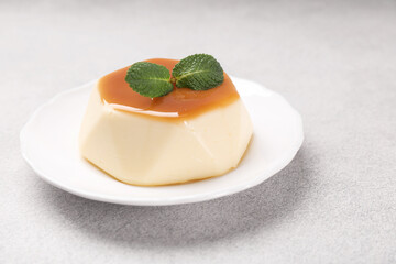 Delicious pudding with caramel sauce and mint on light table, closeup