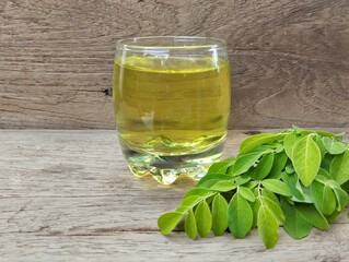 Moringa tea leaves (moringa oleifera) in glass on wooden table background. Healthy drink lifestyle 