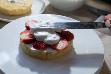 スポンジケーキに生クリームを重ねぬりしてイチゴのショートケーキを作っている