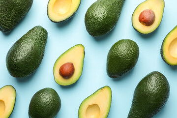 Whole and cut avocados on light blue background, flat lay
