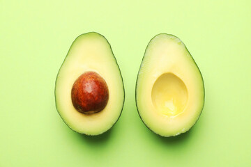 Halves of fresh avocado on light green background, flat lay