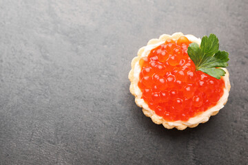 Tasty canape with red caviar on grey table, top view. Space for text