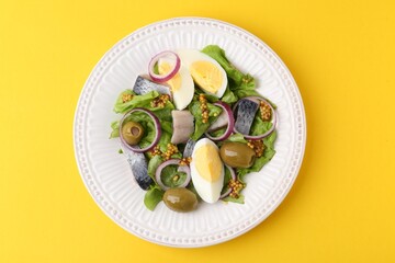 Delicious salad with herring, egg, mustard and vegetables on yellow background, top view