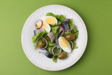 Delicious salad with herring, egg and vegetables on green background, top view