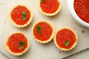 Tartlets with red caviar and parsley on beige background, top view