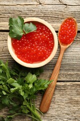 Red caviar and parsley on wooden table, flat lay