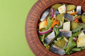 Delicious salad with herring, vegetables and mustard on green background, top view. Space for text