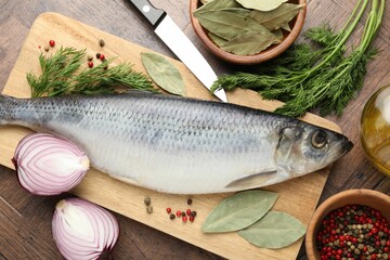 Salted herring, spices and knife on wooden table, flat lay