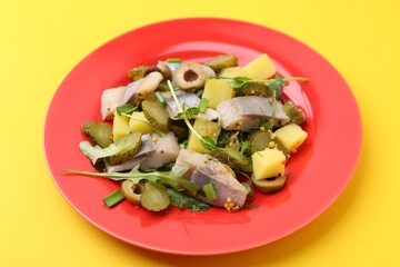 Delicious salad with herring on yellow background, closeup