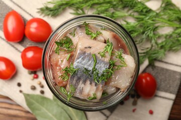 Pieces of delicious herring with dill in jar and tomatoes on table, flat lay