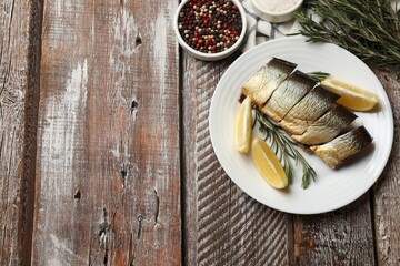 Smoked herring and spices on wooden table, flat lay. Space for text
