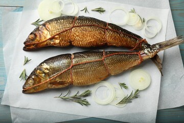 Smoked herrings, rosemary and onion on light blue wooden table, flat lay