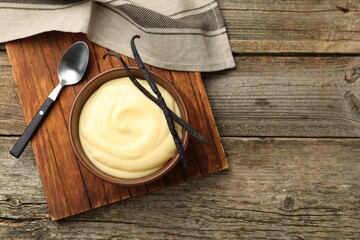 Tasty vanilla pudding and pods on wooden table, flat lay. Space for text