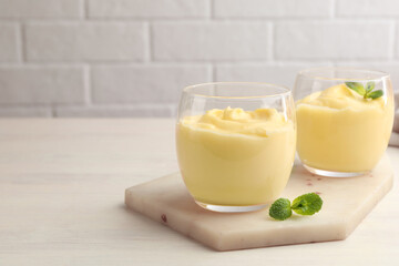Tasty vanilla pudding with mint on white wooden table. Space for text
