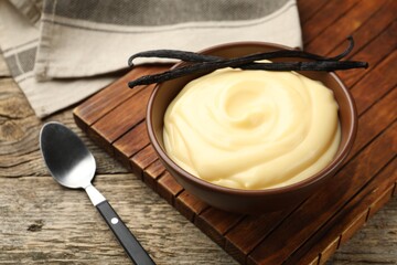 Tasty vanilla pudding and pods served on wooden table, closeup