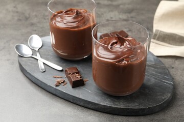 Tasty pudding and pieces of chocolate on grey table, closeup