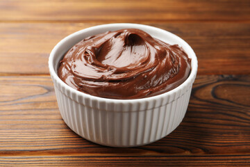 Tasty chocolate pudding in bowl on wooden table, closeup