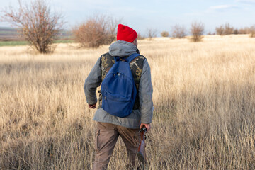 Mature hunter man holding a shotgun and walking through a field