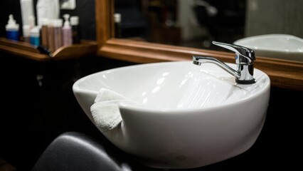 A professional hair salon sink with a sleek design, complete with a chrome faucet and ergonomic neck support. Perfect for salon catalogs or hairstyling promotion projects