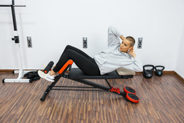 Determined woman performing abdominal crunches on a bench at home gym