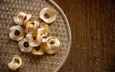 Dried apple slices on a woven tray in a natural setting