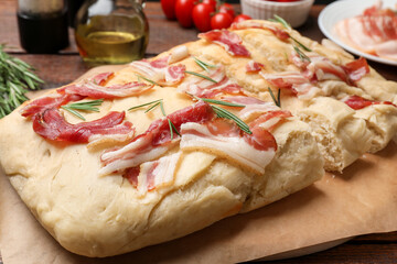 Slices of delicious focaccia bread with bacon and rosemary on table, closeup