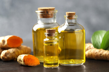 Tumeric oil and roots on black board, closeup