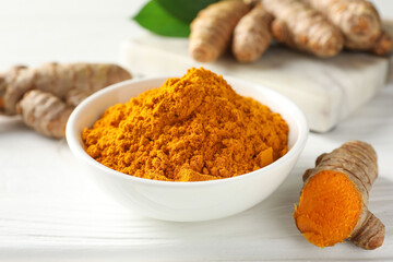 Aromatic turmeric powder and fresh roots on white wooden table, closeup