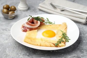 Delicious crepe bretonne with bacon and arugula on grey textured table, closeup