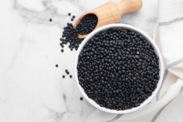 Black lentils on white marble table, flat lay
