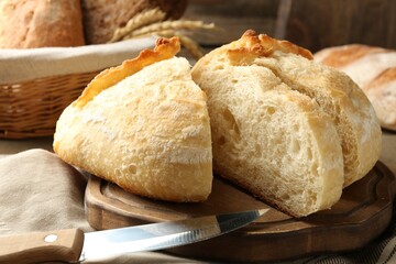 Cut freshly baked bread and knife on table, closeup