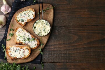 Tasty bread with garlic, herbs and oil on wooden table, flat lay. Space for text