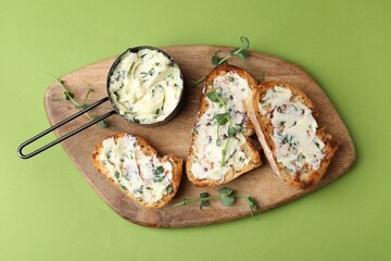 Tasty bread with garlic, herbs and oil on light green background, top view
