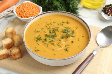 Delicious lentil cream soup with dill and ingredients on white table, closeup